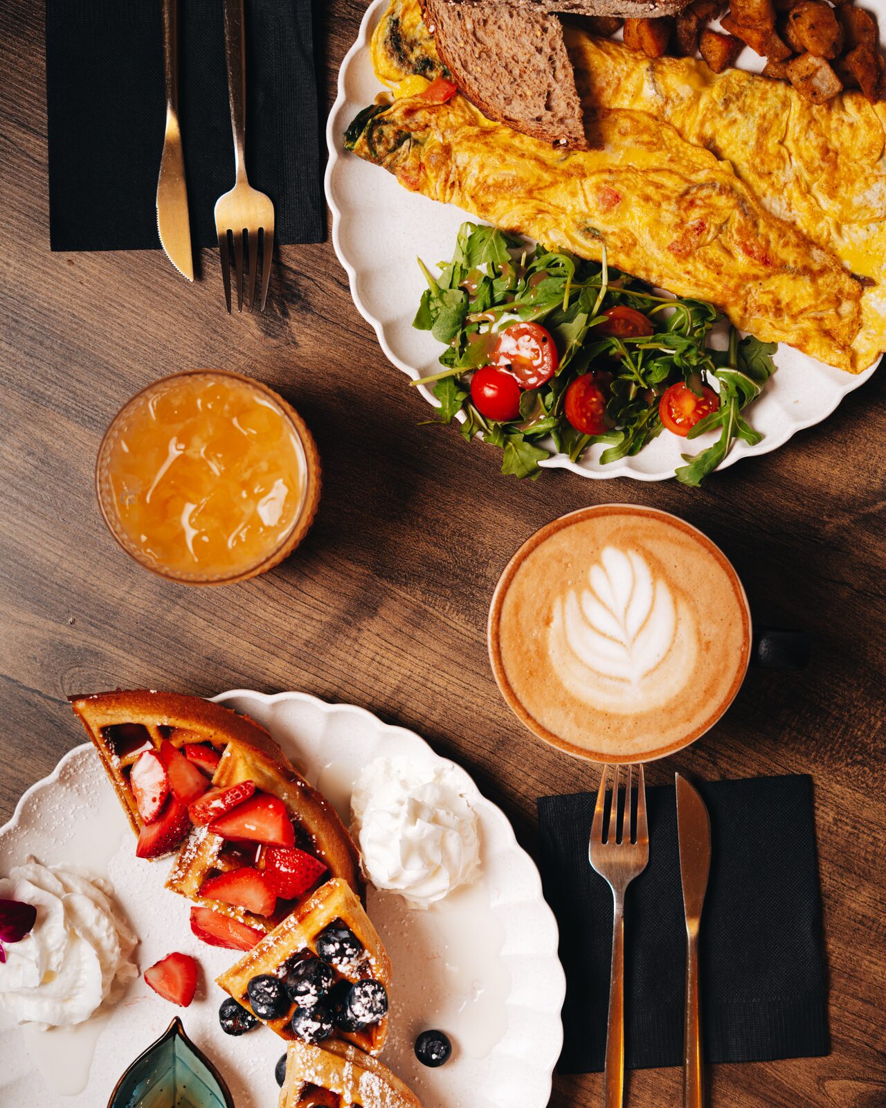 Full brunch spread with omelette, waffles, latte, and juice