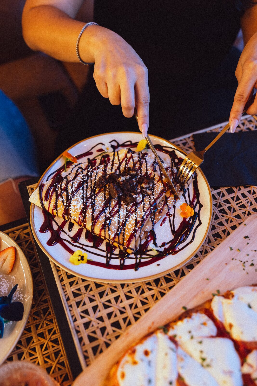 Two people sharing a chocolate crepe with edible flowers