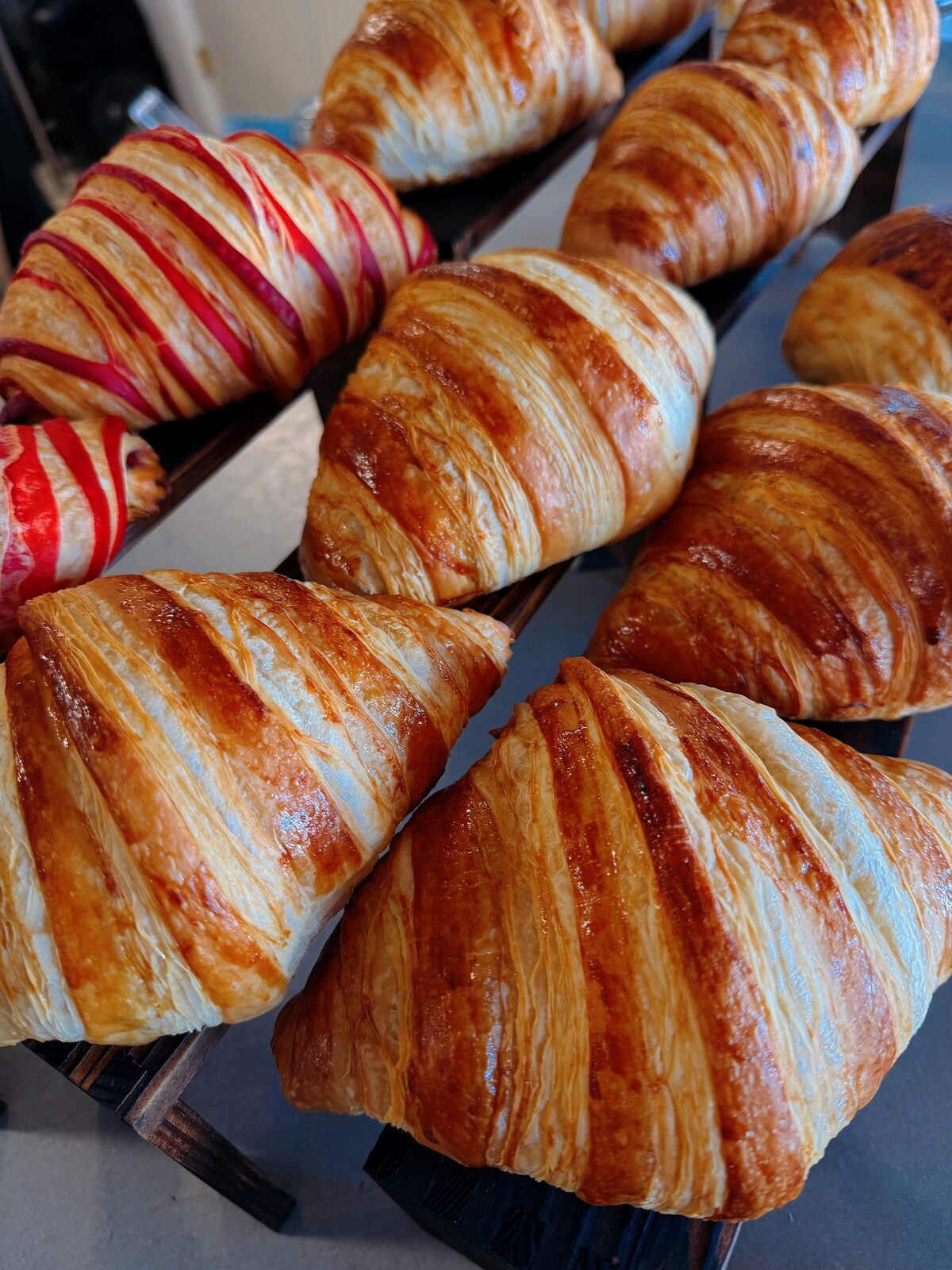 Fresh croissants on a rack, plain and raspberry-glazed