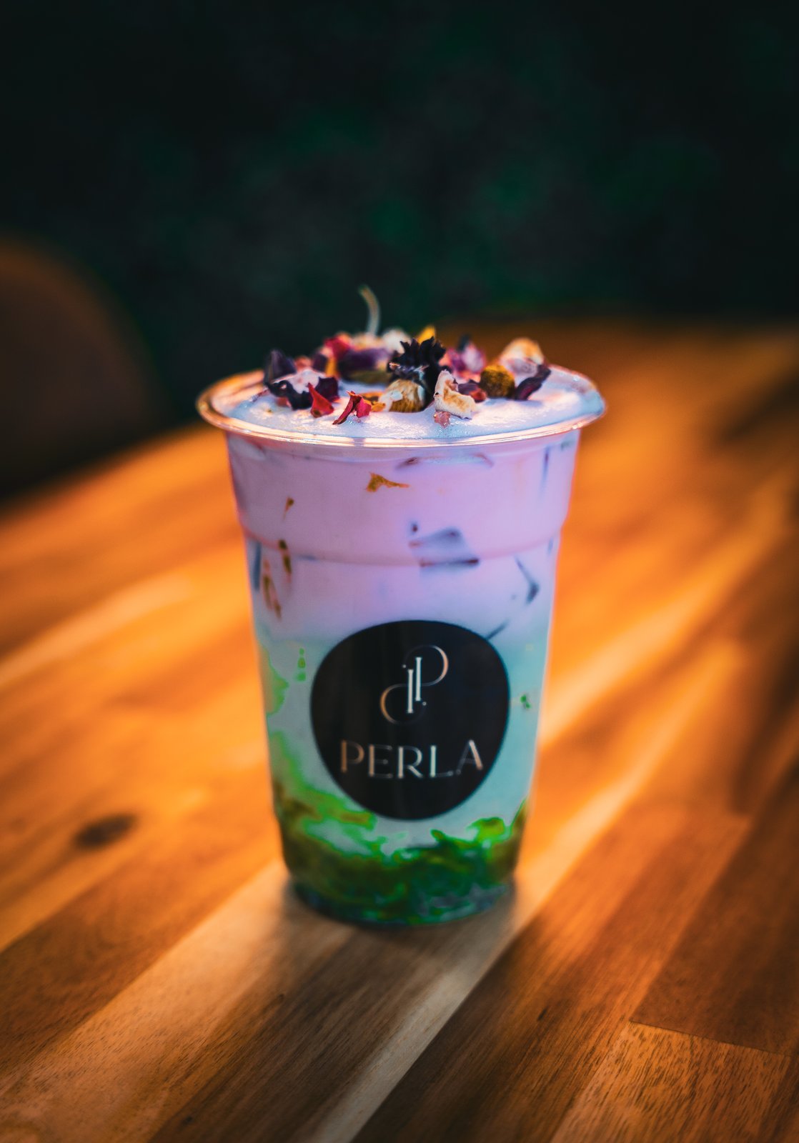 Iced signature Perla drink with rose petals and pistachio crumble in a branded cup